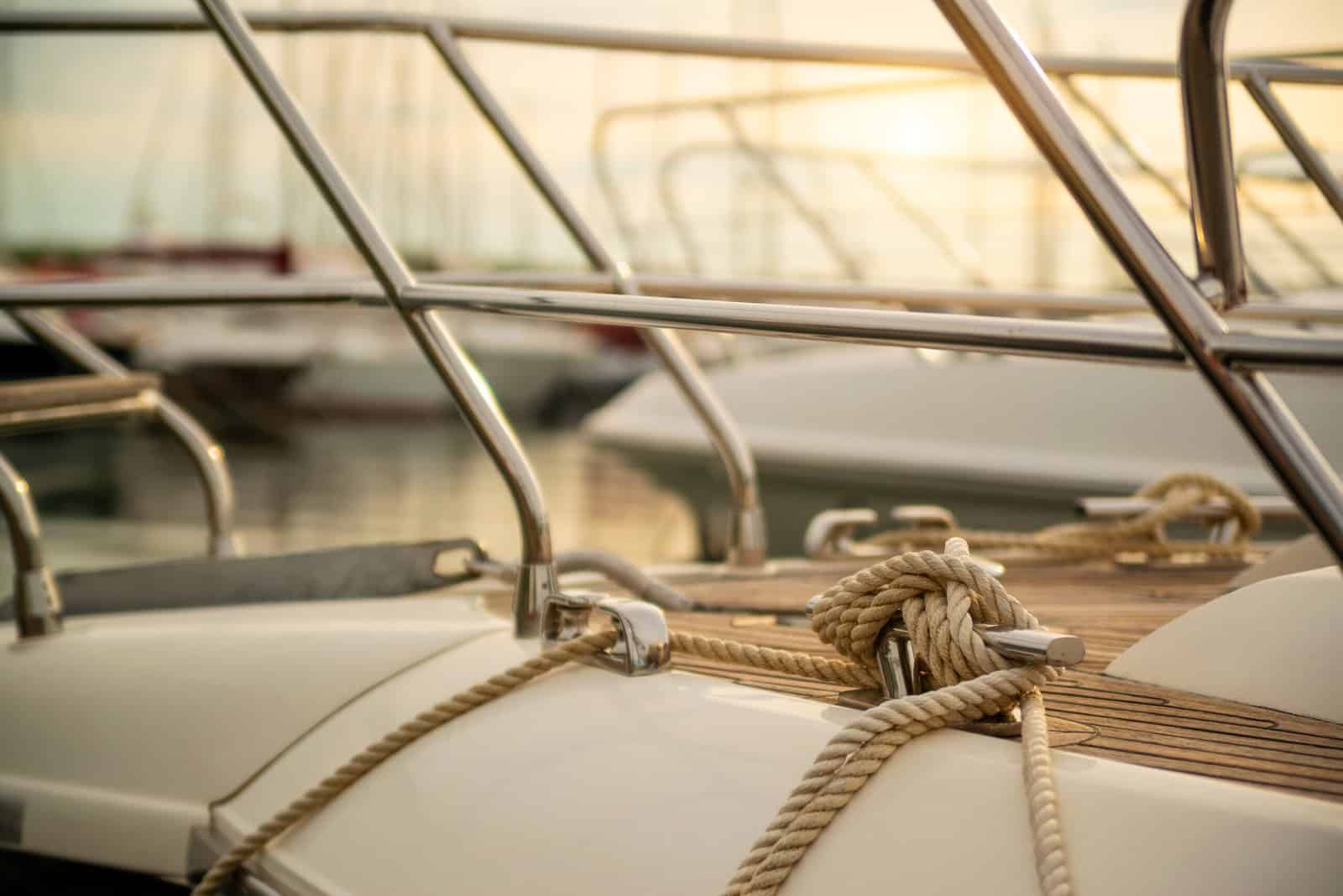 White mooring rope tied around steel anchor on boat