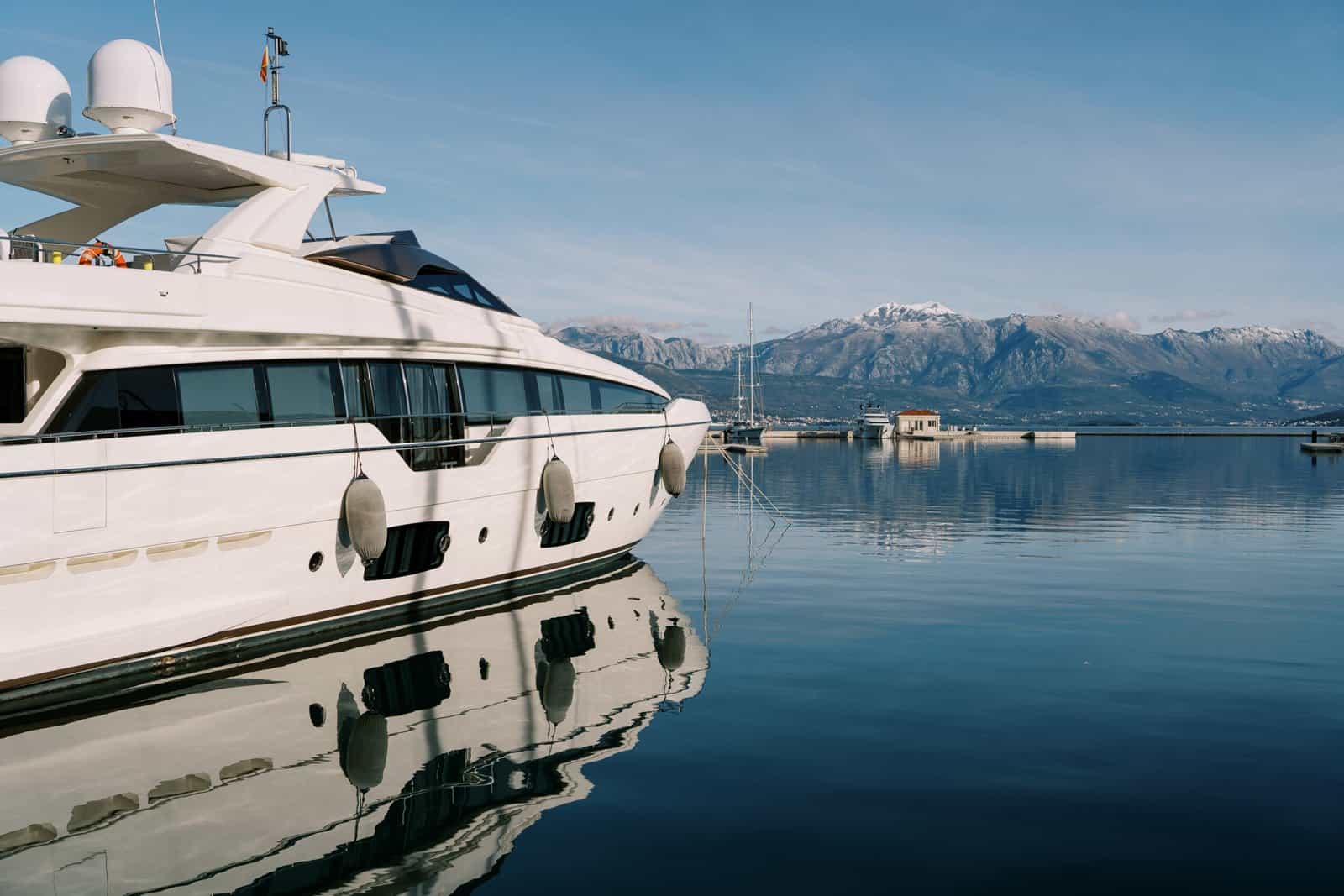 White double-deck yacht is moored at the pier against the backdrop of the mountains